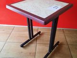 a small table with a red top on a tiled floor