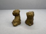 deux petites figurines de chiens en laiton posées sur une surface blanche