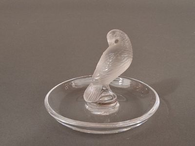a glass figurine of a bird sitting on a glass plate