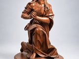 une statue en bronze de Jésus tenant la croix, posée sur un socle en bois