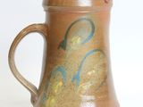 a brown pitcher with blue and yellow designs on it