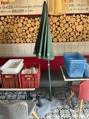 des tables et des chaises devant un magasin avec un parasol vert