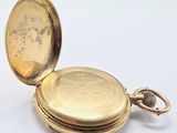 an antique gold pocket watch with a chain hanging from it ' s side