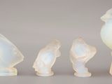 trois figurines d'oiseaux en verre et un oiseau posé sur une table
