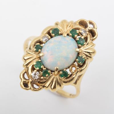 a close up of a ring with an oplite and emerald stones