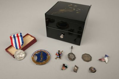 une petite boîte contenant des médailles et sur laquelle est posée une médaille