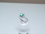 a ring with a green stone on it sitting on a clear glass