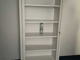 a white book shelf with a phone on it in the corner of a room