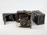 two old cameras sitting next to each other on a white surface