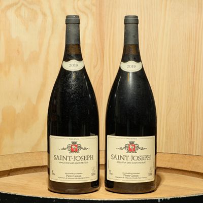 two bottles of wine sitting on top of a barrel next to each other