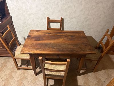 a wooden table with four chairs and a cabinet in the corner