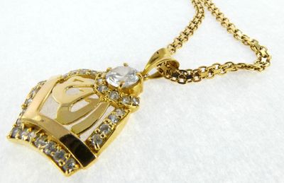 a close up of a gold necklace with a crown on it