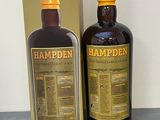 La bouteille de Hampden se trouve à côté de la boîte, sur la table.