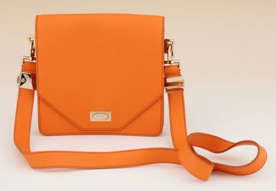an orange cross body bag with a strap on a white background