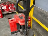 a red and black fork lifter in a warehouse