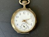 une petite montre de poche en or posée sur une surface noire