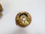 une petite horloge en or posée sur une table, à côté d'un petit objet en or