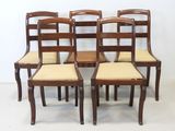 quatre chaises en bois avec des assises rembourrées beiges et une petite table