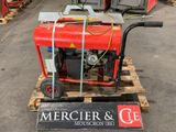 un petit générateur rouge posé sur une palette dans un entrepôt