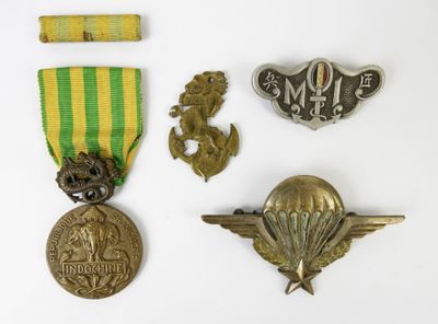 Plusieurs médailles et insignes militaires sont exposés sur un fond blanc