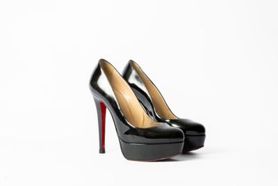 une paire de talons hauts noirs posée sur une surface blanche