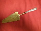couteau à fromage ancien plaqué argent posé sur un tissu rouge, sur un tissu rouge