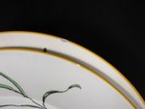 a close up of a plate with a flower painted on it