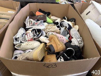 many pairs of shoes in a cardboard box on the floor