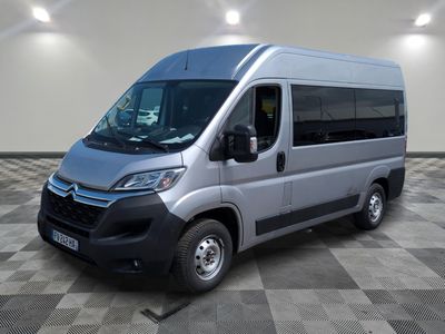 La camionnette argentée est garée dans une grande pièce au sol carrelé en damier.