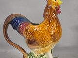a ceramic rooster that is standing on the grass