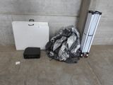 une photo montrant une valise, un trépied et d'autres objets posés sur un sol en béton