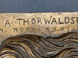 a bronze plaque of a woman with long hair