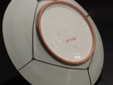 a white plate with a brown rim sitting on a black surface