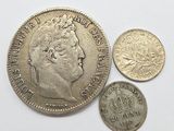 Trois pièces britanniques, une en argent et une en or, sont posées sur une surface blanche