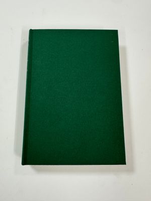 a green book sitting on top of a table next to a white wall