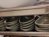 many bowls and pans stacked on a metal shelf