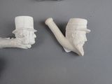 three clay figurines of a man with a pipe and a hat
