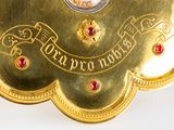 a gold clock with red jewels on it