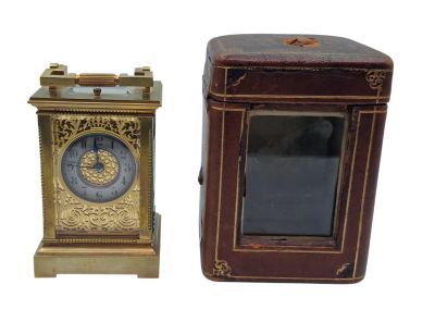une petite horloge posée à côté d'une petite boîte sur une surface blanche