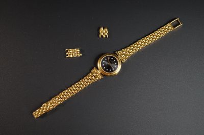 gros plan d'une montre en or sur une surface noire