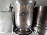 a silver vase sitting next to two other silver containers