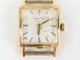 a gold watch with a white face on a white surface