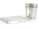 une coupe en argent posée à côté d'un coffret en argent sur une surface blanche