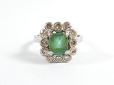 une image d'une bague avec une pierre verte entourée de diamants blancs