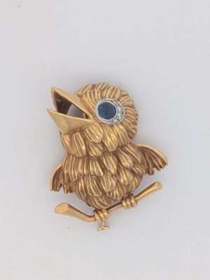 un oiseau doré aux yeux bleus, perché sur une branche
