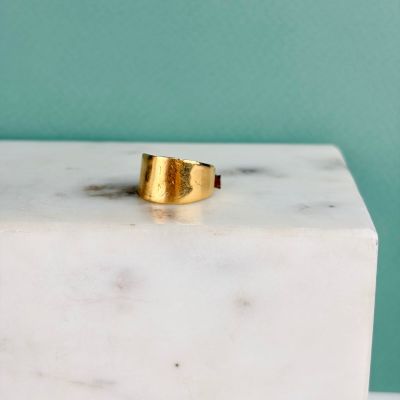 La bague en or repose sur un bloc de marbre blanc