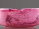un bol en marbre rose posé sur une table, dont la surface reflète une image