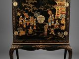 une vitrine peinte en noir et or, posée sur un socle
