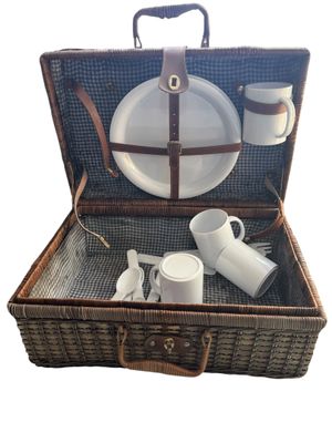 un panier de pique-nique en osier contenant des assiettes et des tasses