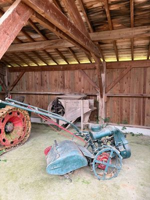 un vieux tracteur et une charrue dans une grange